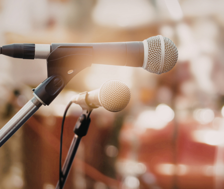 Two modern microphones on stands on a stage.
